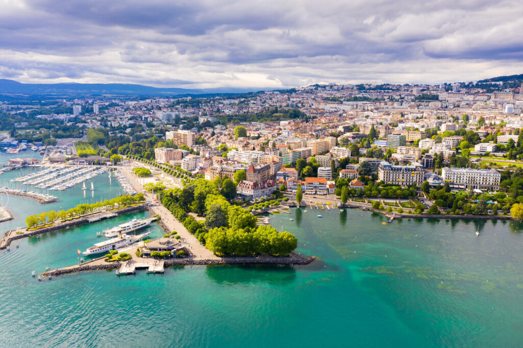 Panoramic view of Lausanne city skyline against Lake Geneva at dusk.